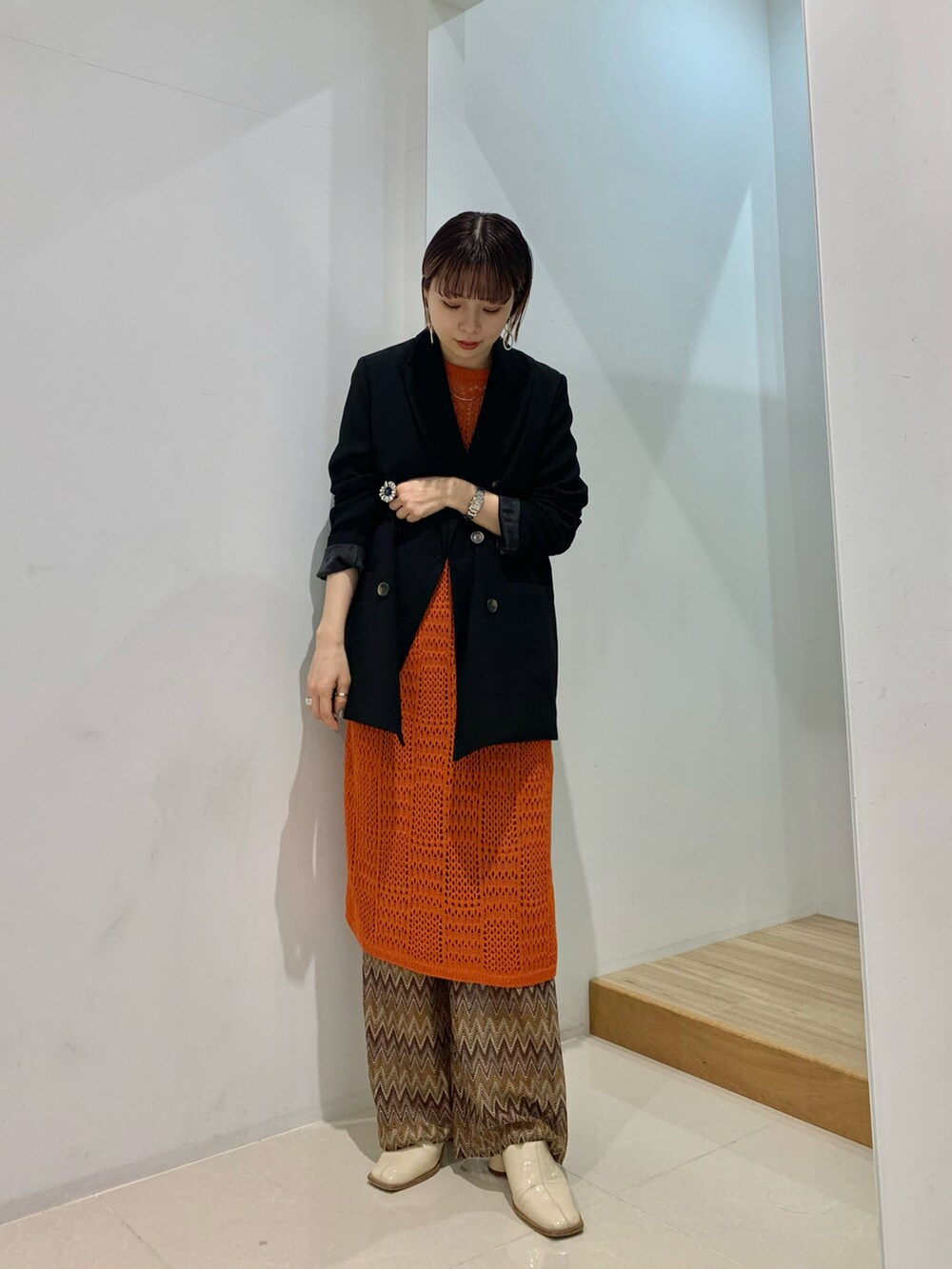 ブラック系のテーラードジャケット、オレンジ系のベスト、ブラウン系のその他パンツを着用したレディースの春コーディネートの2枚目の写真