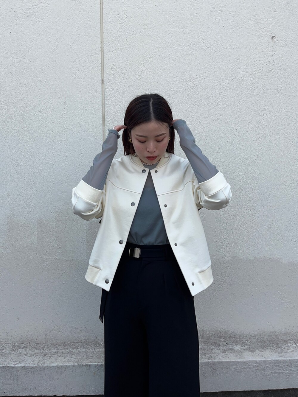 ホワイト系のブルゾン、グリーン系のTシャツ/カットソー、ブラック系のスラックスを着用したレディースの春コーディネートの5枚目の写真