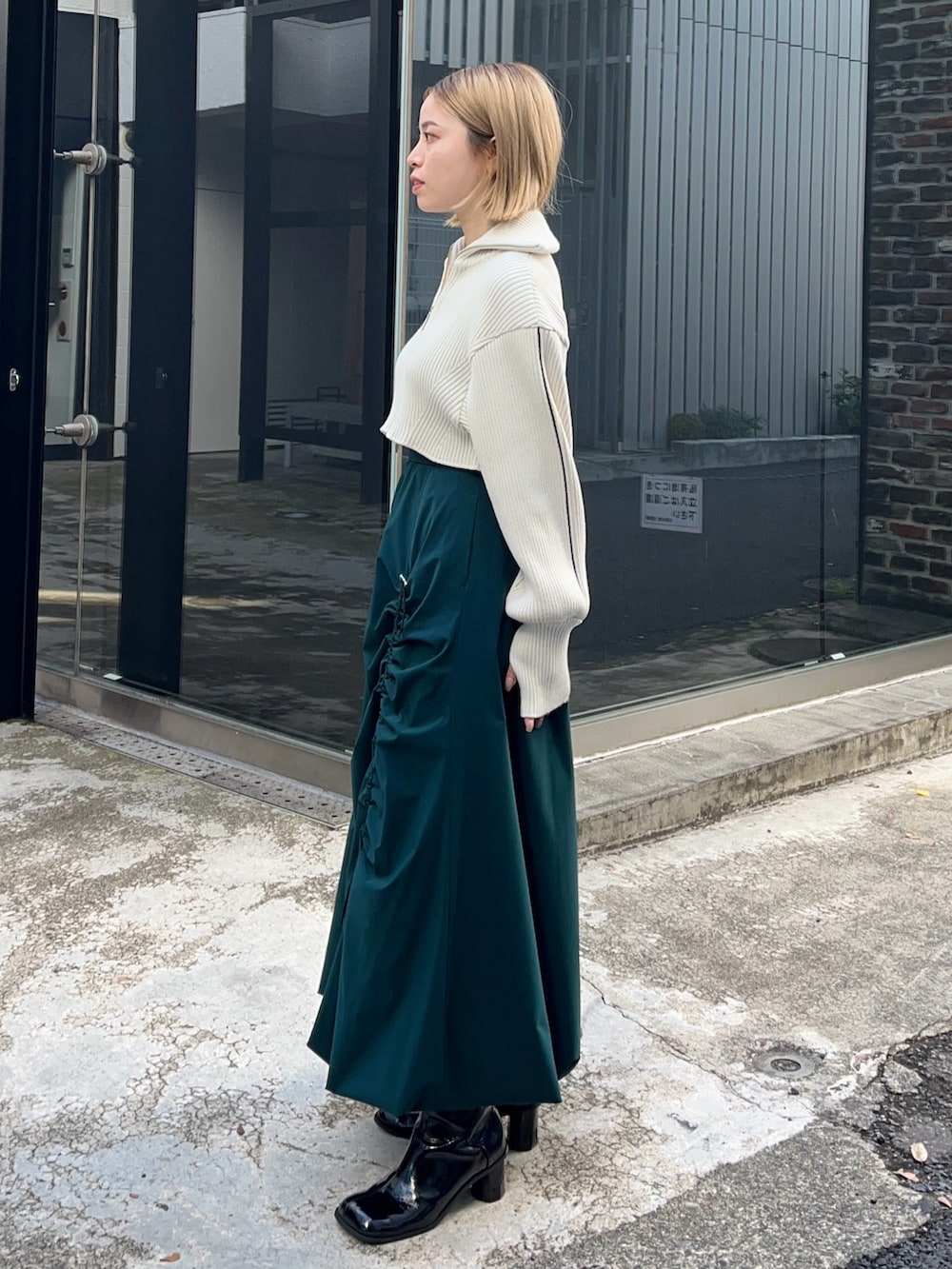 グリーン系のスカート、ホワイト系のニット/セーターを着用したレディースの冬コーディネートの2枚目の写真