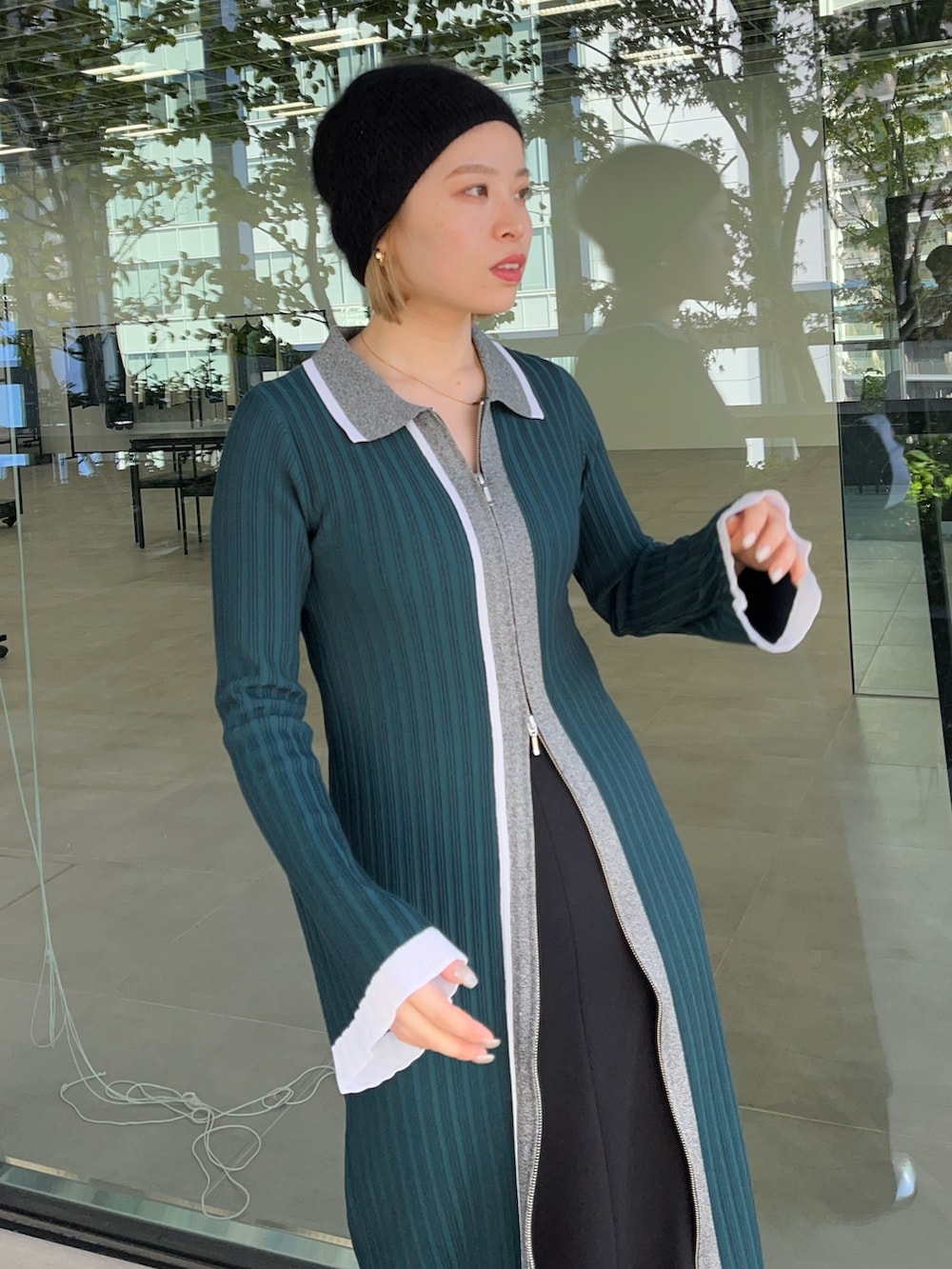 グリーン系のワンピース、ホワイト系のスカート、シルバー系のブーツを着用したレディースの冬コーディネートの3枚目の写真