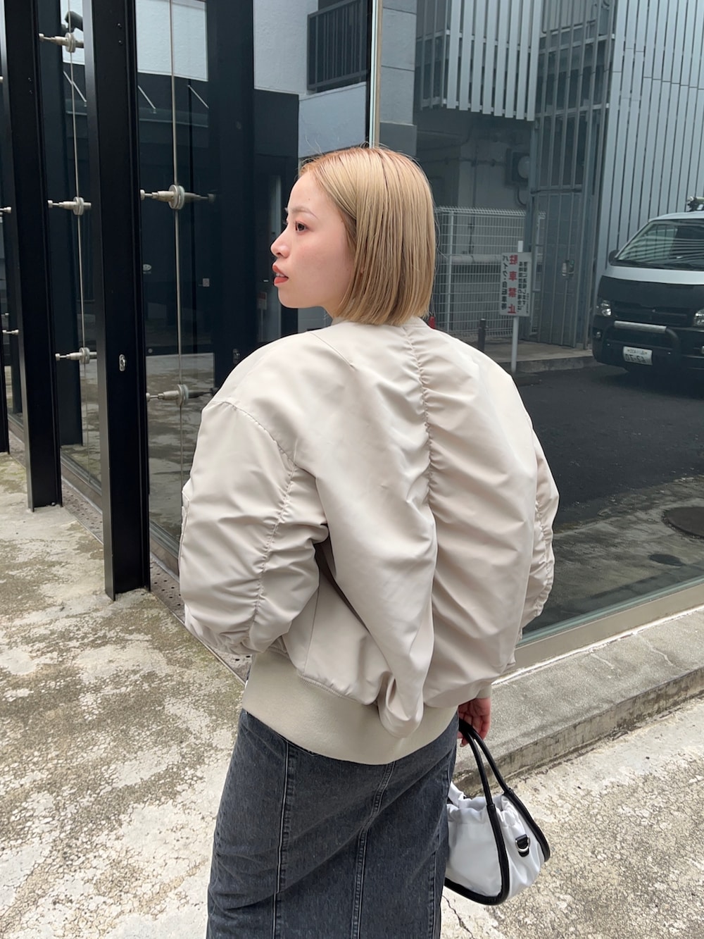 ホワイト系のMA-1、グリーン系のTシャツ/カットソー、ブラック系のデニムスカートを着用したレディースの秋コーディネートの5枚目の写真