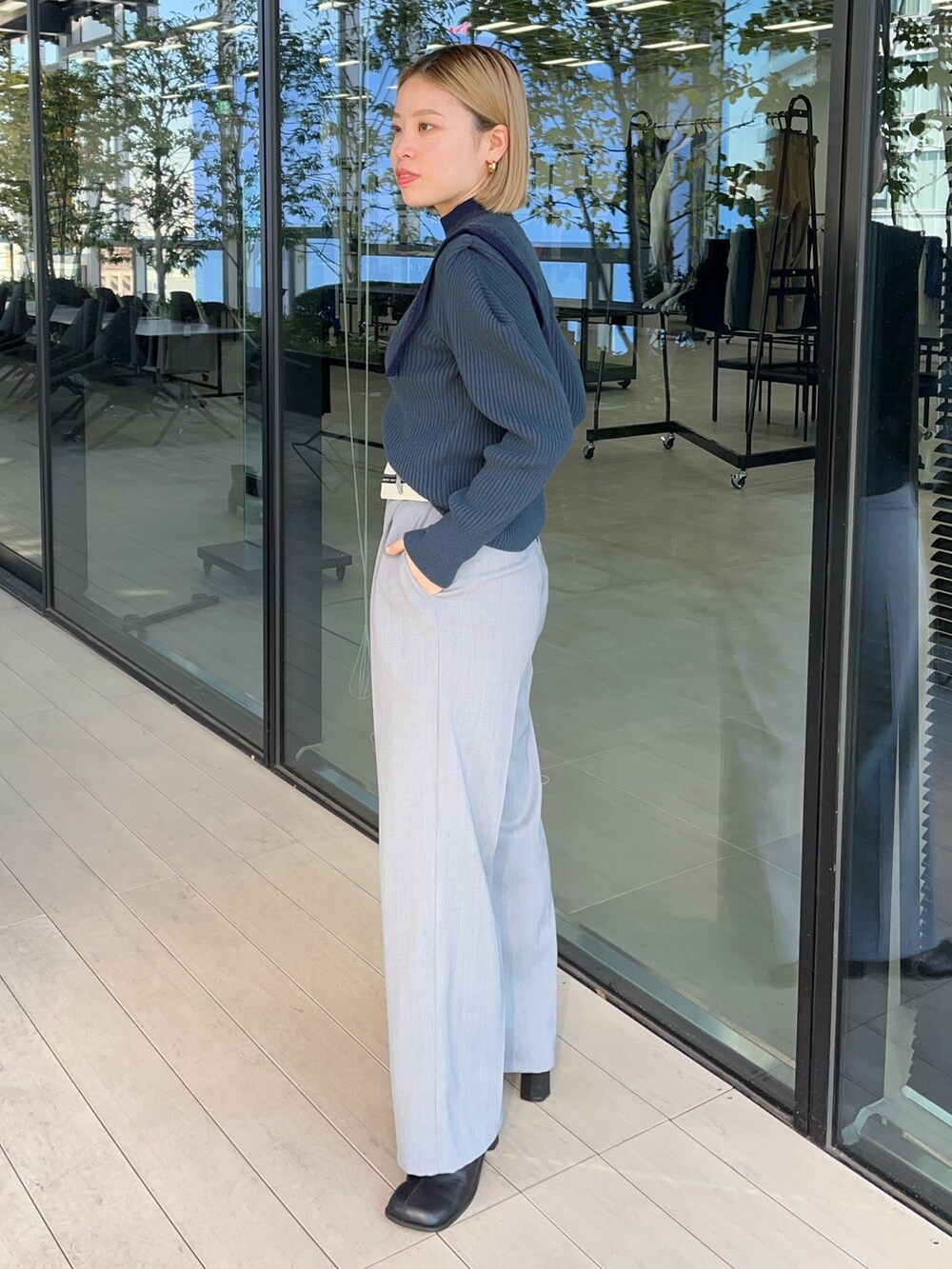 ブルー系のニット/セーター、グレー系のスラックスを着用したレディースの冬コーディネートの2枚目の写真