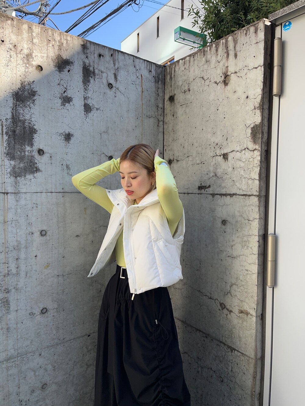 グリーン系のTシャツ/カットソー、ホワイト系のダウンジャケット/コート、ブラック系のスカートを着用したレディースの秋コーディネートの4枚目の写真