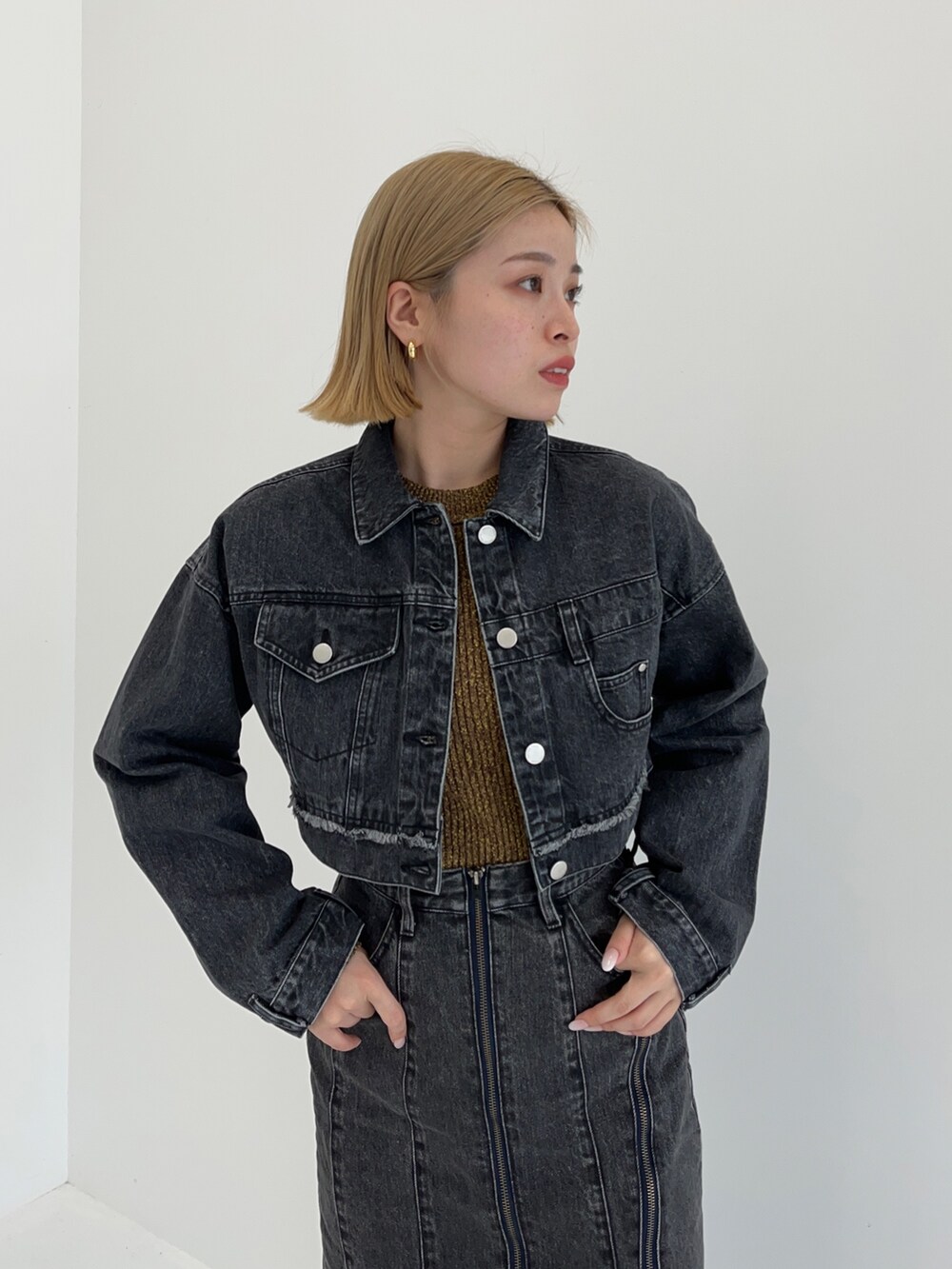 ブラック系のデニムスカート、イエロー系のニット/セーター、ブラック系のデニムジャケットを着用したレディースの秋コーディネートの3枚目の写真