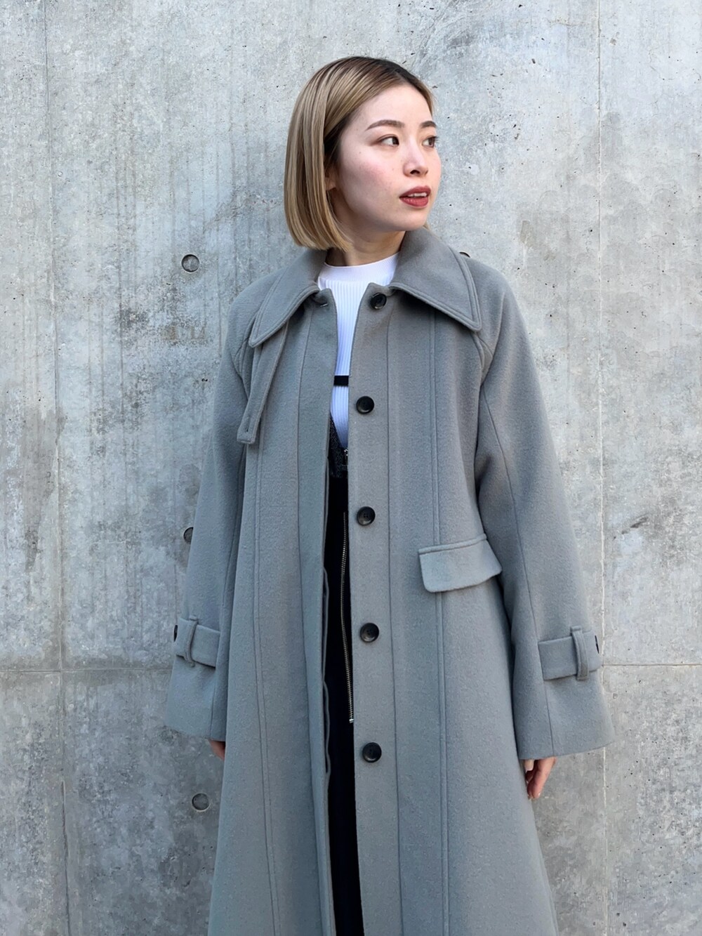 グリーン系のステンカラーコートを着用したレディースの冬コーディネートの6枚目の写真