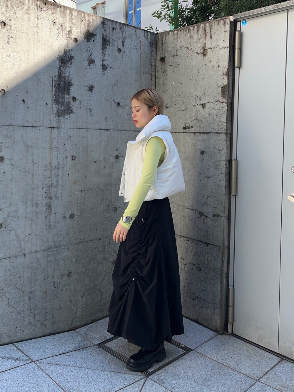 グリーン系のTシャツ/カットソー、ホワイト系のダウンジャケット/コート、ブラック系のスカートを着用したレディースの秋コーディネートの5枚目の写真