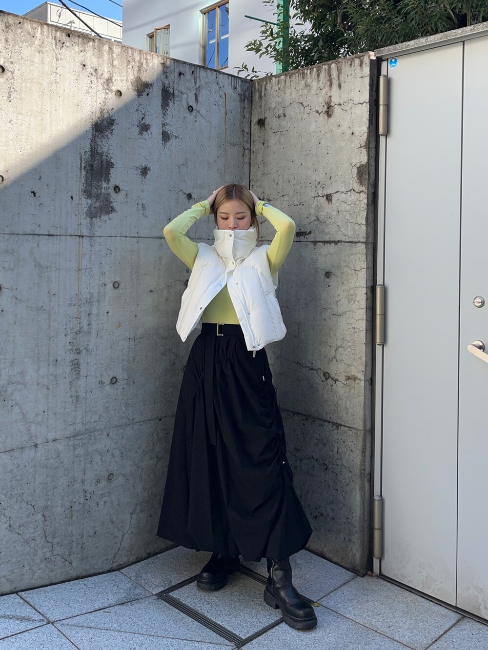 グリーン系のTシャツ/カットソー、ホワイト系のダウンジャケット/コート、ブラック系のスカートを着用したレディースの秋コーディネートの3枚目の写真