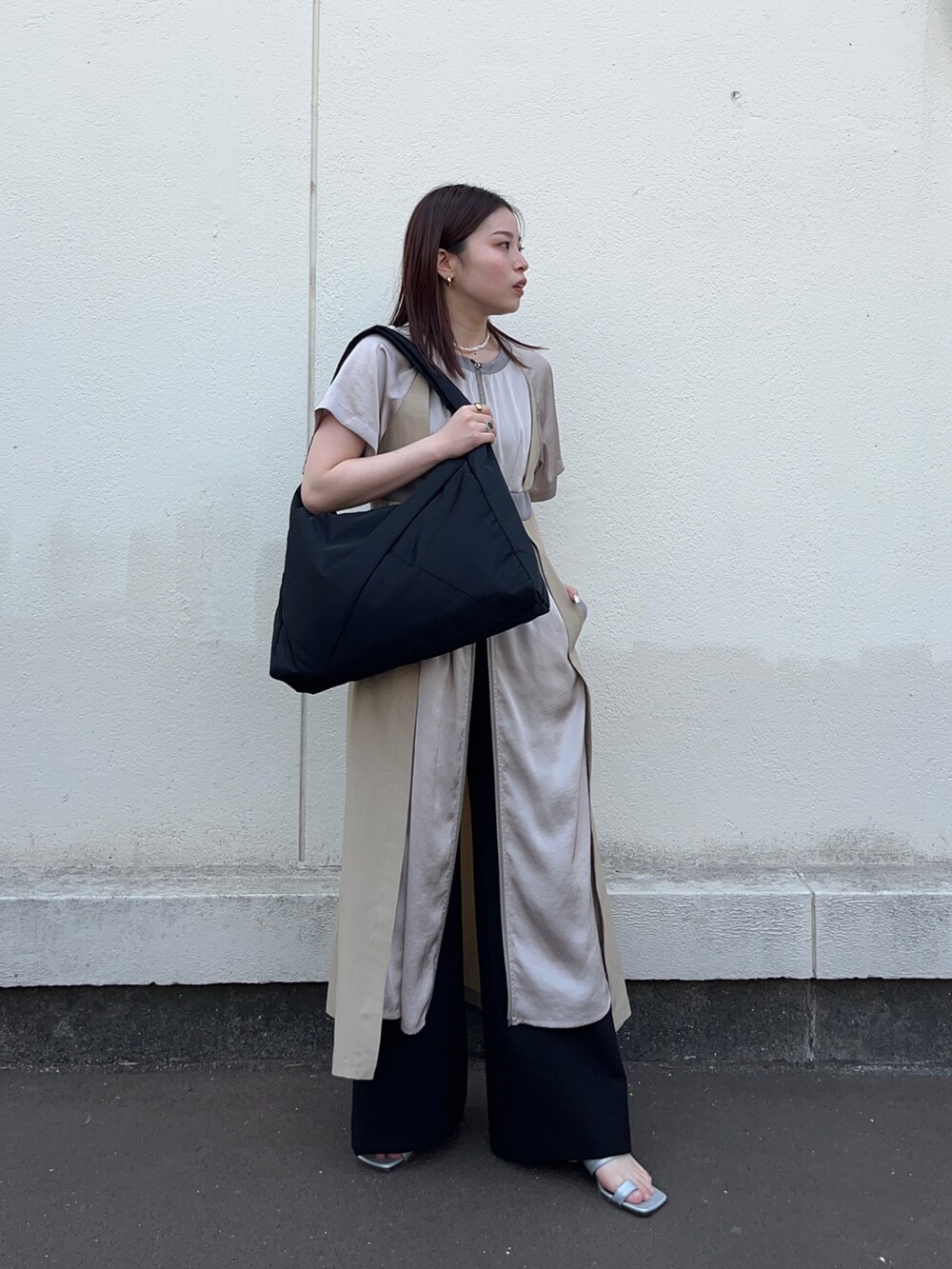 ブラック系のスラックス、ベージュ系のワンピース、ブラック系のトートバッグを着用したレディースの春コーディネートの2枚目の写真