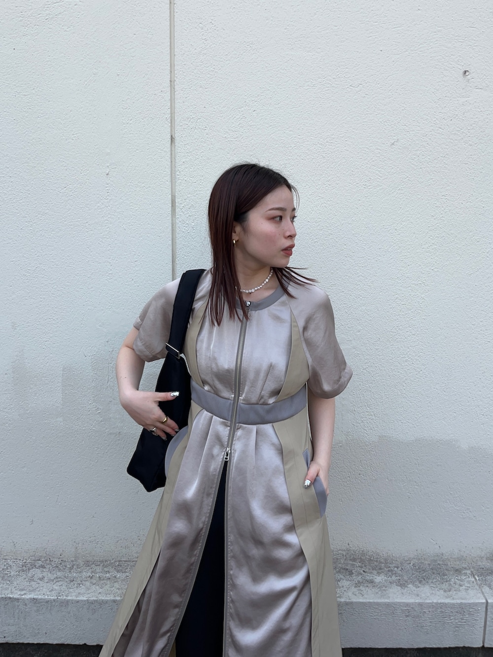 ブラック系のスラックス、ベージュ系のワンピース、ブラック系のトートバッグを着用したレディースの春コーディネートの4枚目の写真