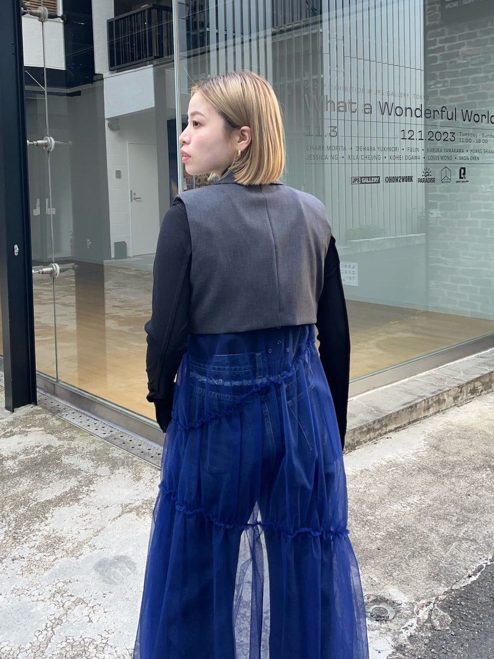 グレー系のワンピース、ブルー系のデニムパンツ、ブラック系のTシャツ/カットソーを着用したレディースの秋コーディネートの3枚目の写真