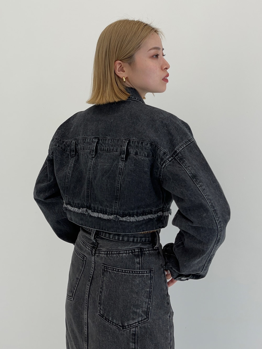 ブラック系のデニムスカート、イエロー系のニット/セーター、ブラック系のデニムジャケットを着用したレディースの秋コーディネートの4枚目の写真