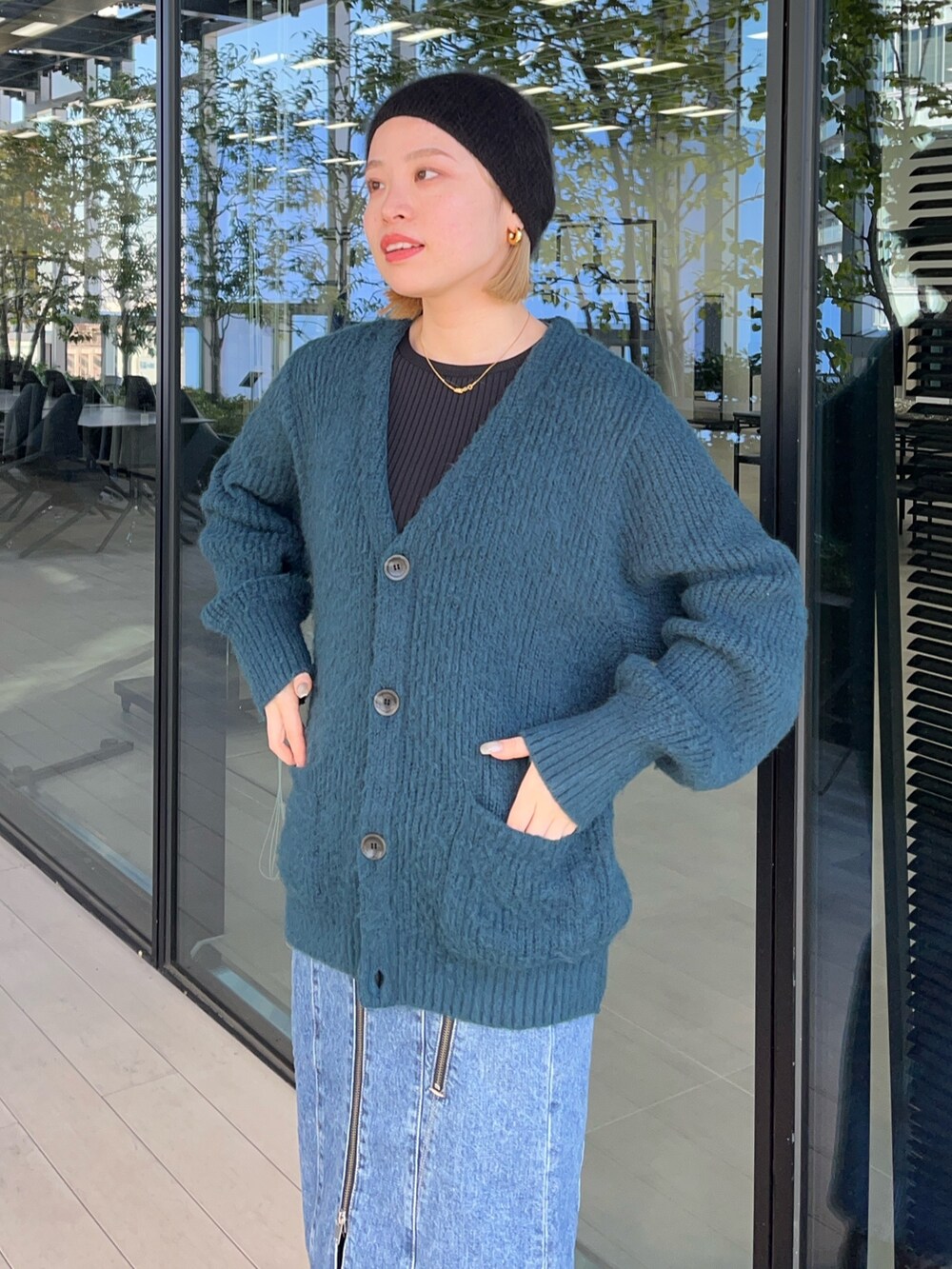 グリーン系のカーディガン/ボレロ、ブルー系のデニムスカートを着用したレディースの秋コーディネートの4枚目の写真