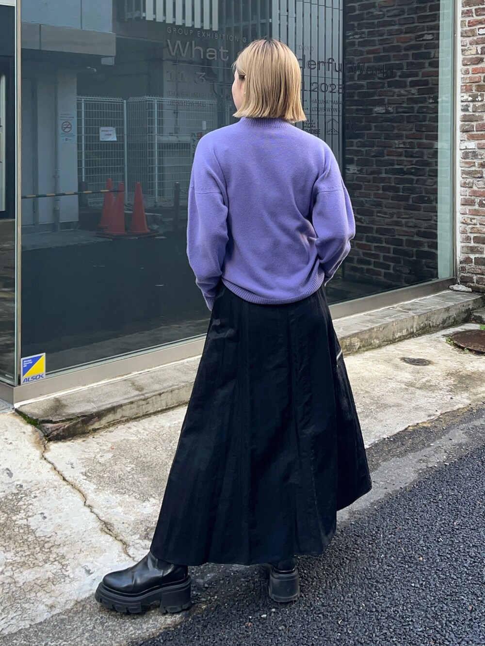 パープル系のニット/セーター、ブラック系のスカートを着用したレディースの冬コーディネートの2枚目の写真