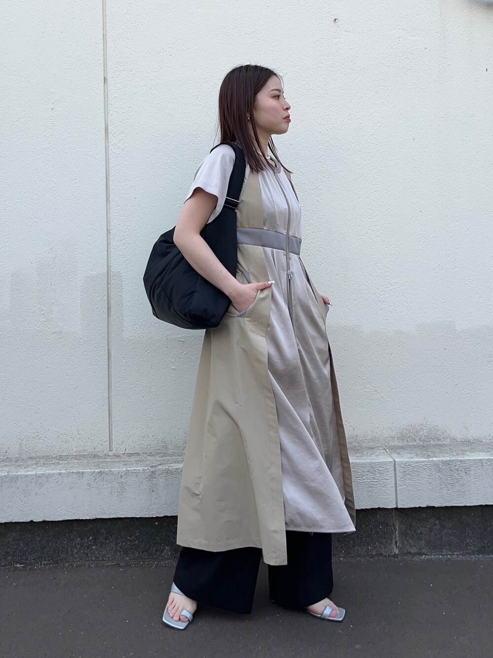 ブラック系のスラックス、ベージュ系のワンピース、ブラック系のトートバッグを着用したレディースの春コーディネートの3枚目の写真