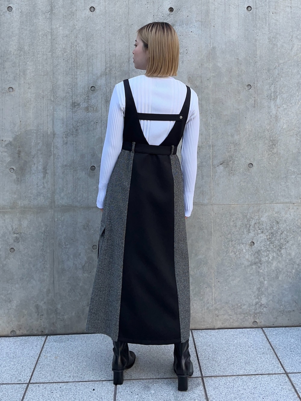 ブラック系のジャンパースカート、ホワイト系のニット/セーターを着用したレディースの冬コーディネートの3枚目の写真