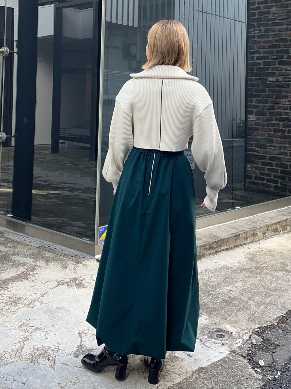 グリーン系のスカート、ホワイト系のニット/セーターを着用したレディースの冬コーディネートの3枚目の写真