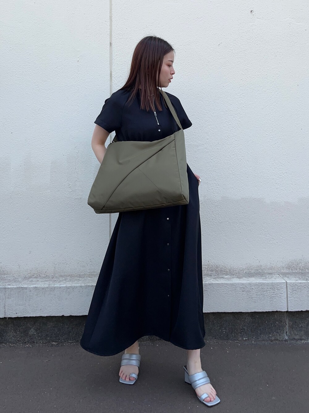 ブラック系のワンピース、グリーン系のトートバッグを着用したレディースの春コーディネートの2枚目の写真