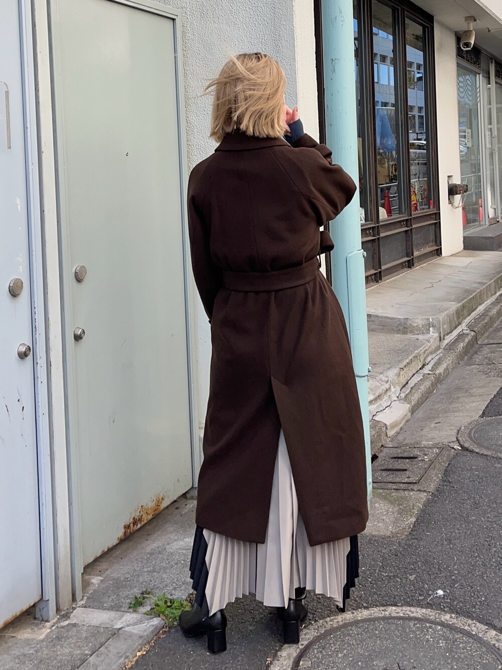 ブラウン系のステンカラーコートを着用したレディースの冬コーディネートの3枚目の写真