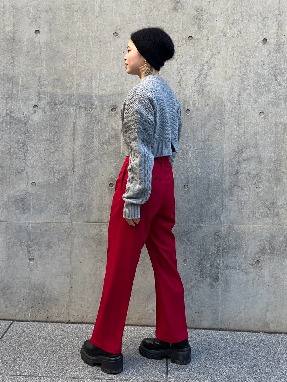 グレー系のニット/セーター、レッド系のその他パンツを着用したレディースの冬コーディネートの2枚目の写真