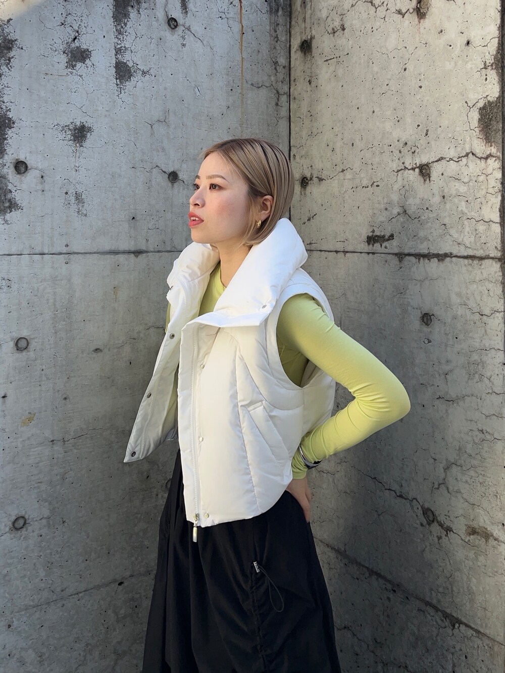 グリーン系のTシャツ/カットソー、ホワイト系のダウンジャケット/コート、ブラック系のスカートを着用したレディースの秋コーディネートの2枚目の写真