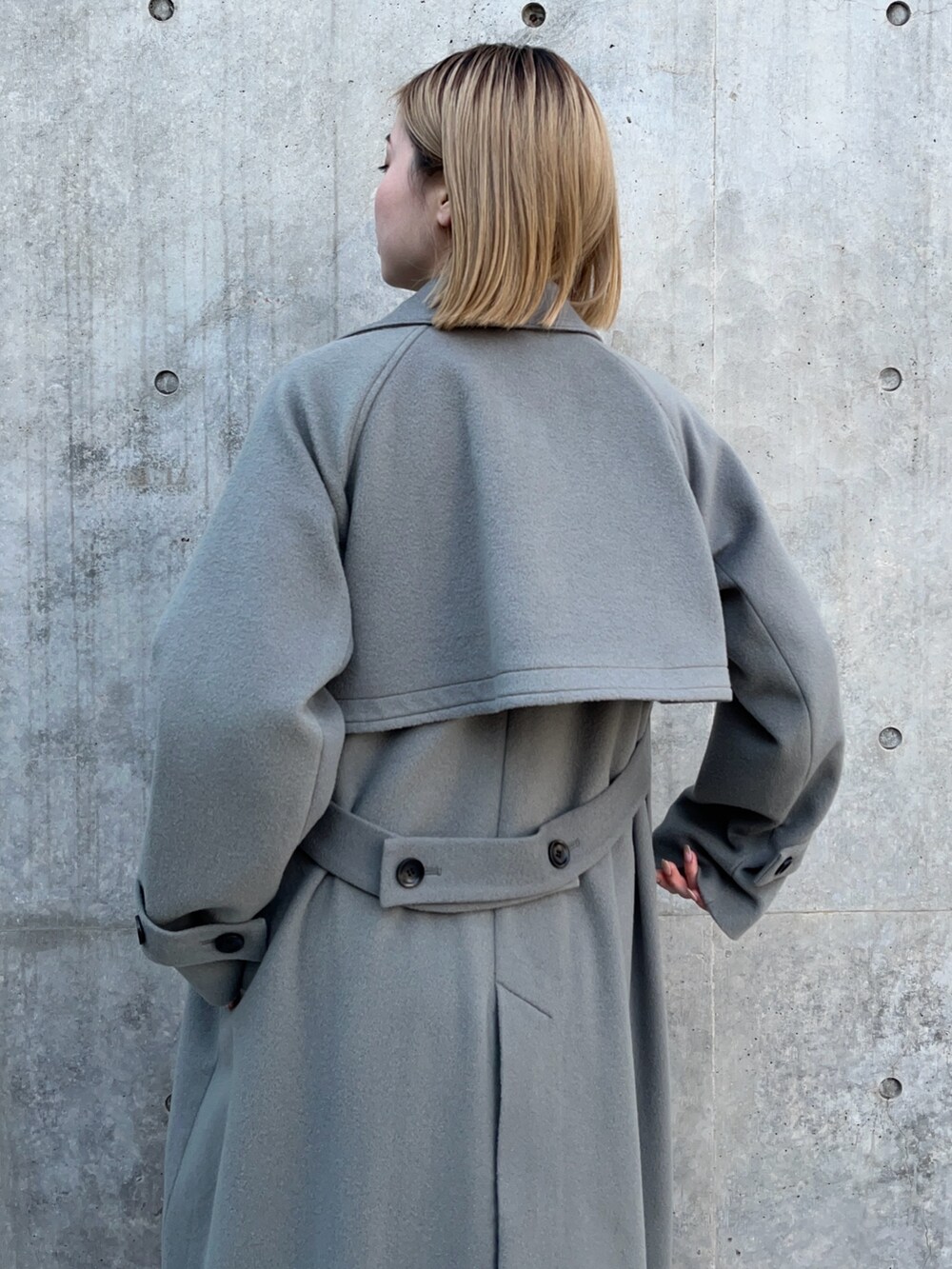 グリーン系のステンカラーコートを着用したレディースの冬コーディネートの4枚目の写真