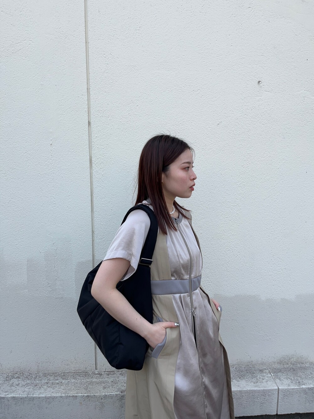 ブラック系のスラックス、ベージュ系のワンピース、ブラック系のトートバッグを着用したレディースの春コーディネートの5枚目の写真