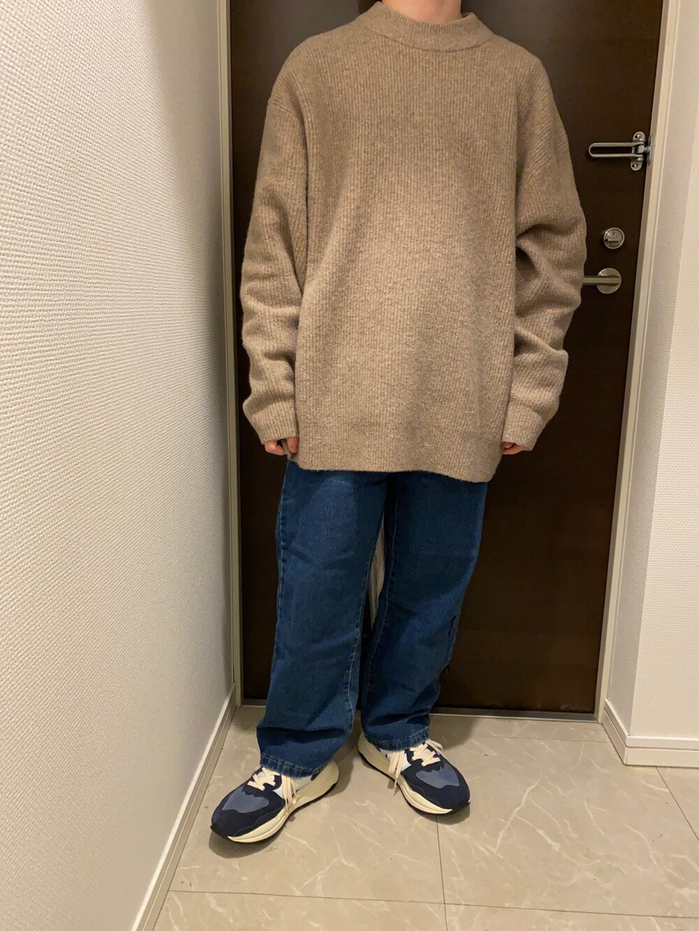 グリーン系のダウンジャケット/コート、ベージュ系のニット/セーター、ブルー系のデニムパンツを着用したメンズの冬コーディネートの2枚目の写真