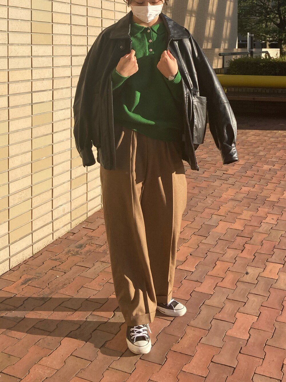 ブラック系のライダースジャケット、グリーン系のニット/セーター、ブラック系のスニーカーを着用したレディースの秋コーディネートの2枚目の写真