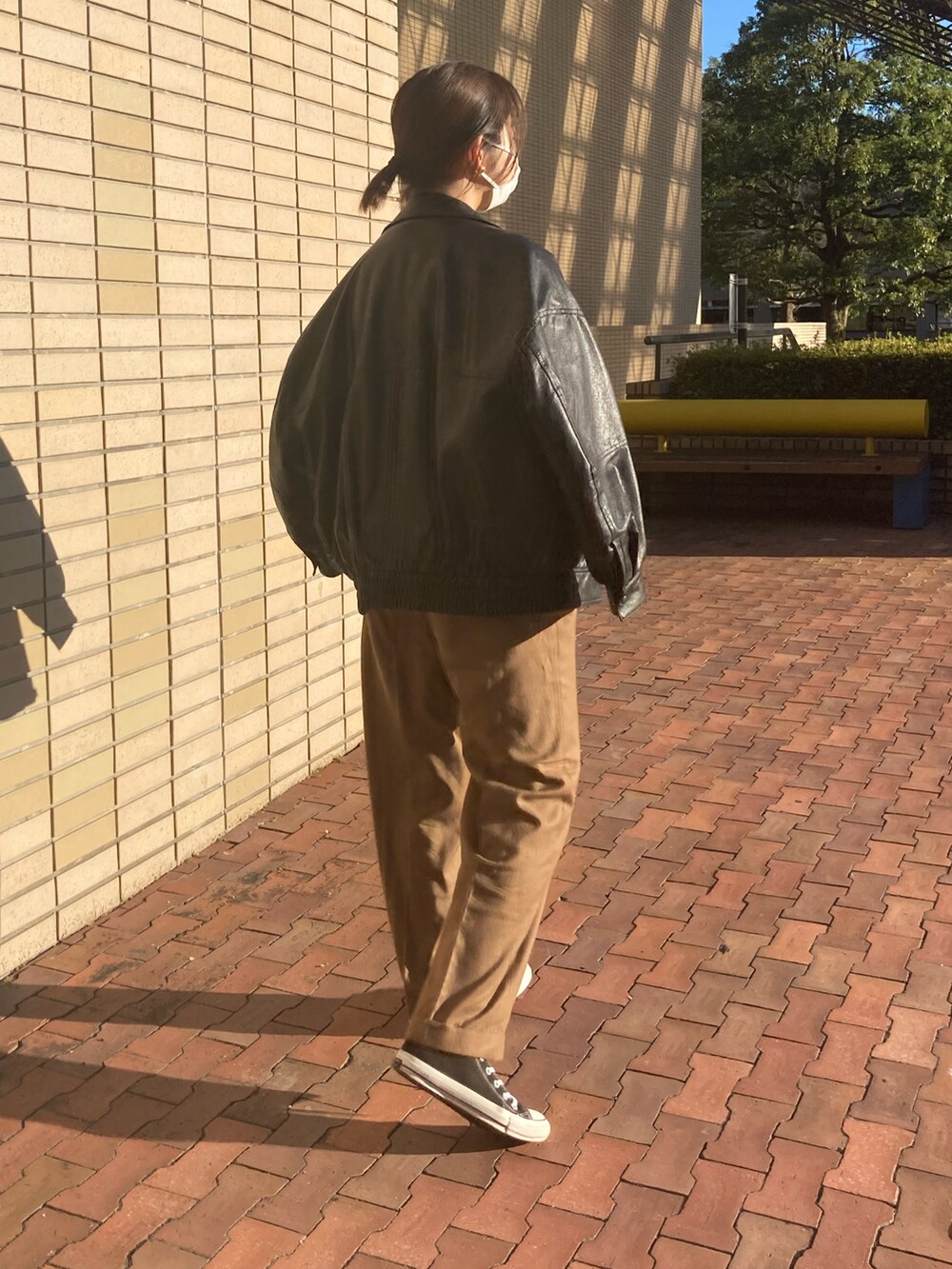 ブラック系のライダースジャケット、グリーン系のニット/セーター、ブラック系のスニーカーを着用したレディースの秋コーディネートの3枚目の写真