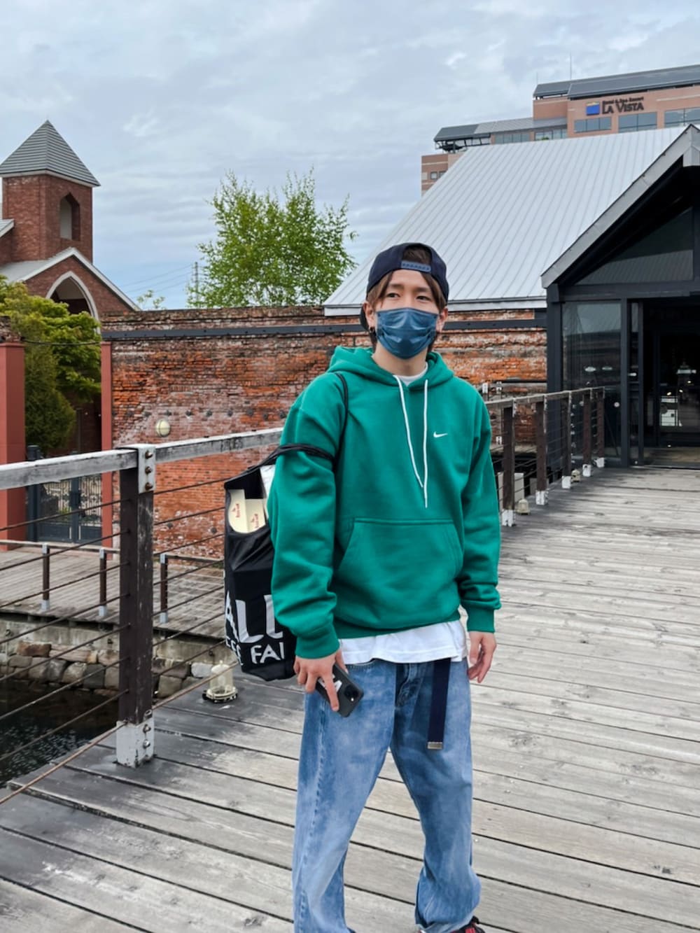 グリーン系のパーカー、ホワイト系のTシャツ/カットソー、ブルー系のデニムパンツを着用したメンズの春コーディネートの2枚目の写真