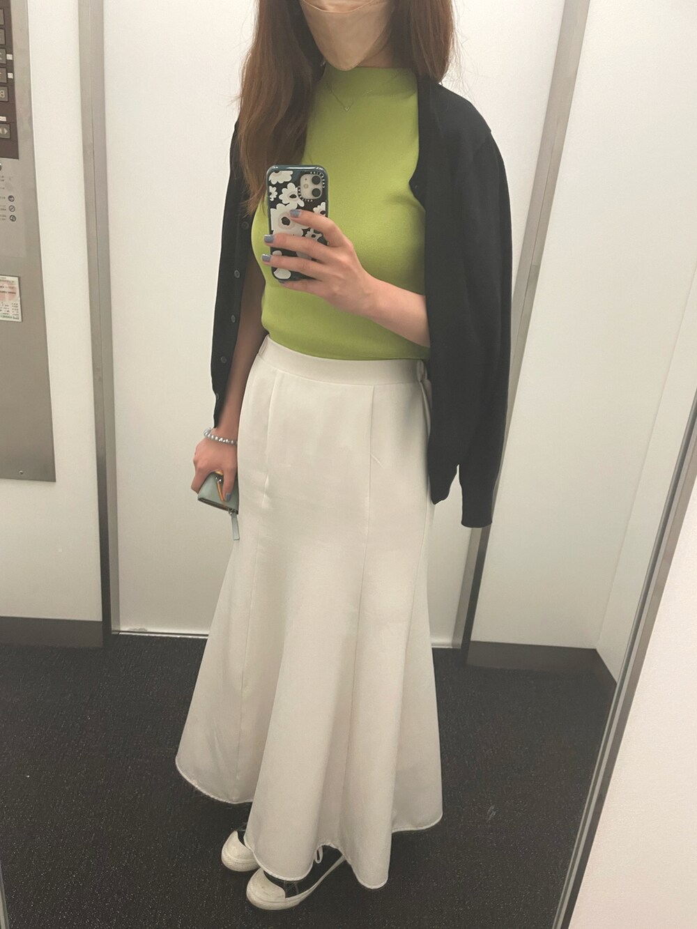 ホワイト系のスカート、グリーン系のニット/セーター、ブラック系のスニーカーを着用したレディースの夏コーディネートの2枚目の写真