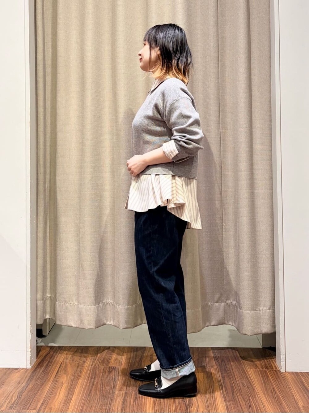 グレー系のニット/セーター、ピンク系のシャツ/ブラウス、ブルー系のデニムパンツを着用したレディースの冬コーディネートの2枚目の写真