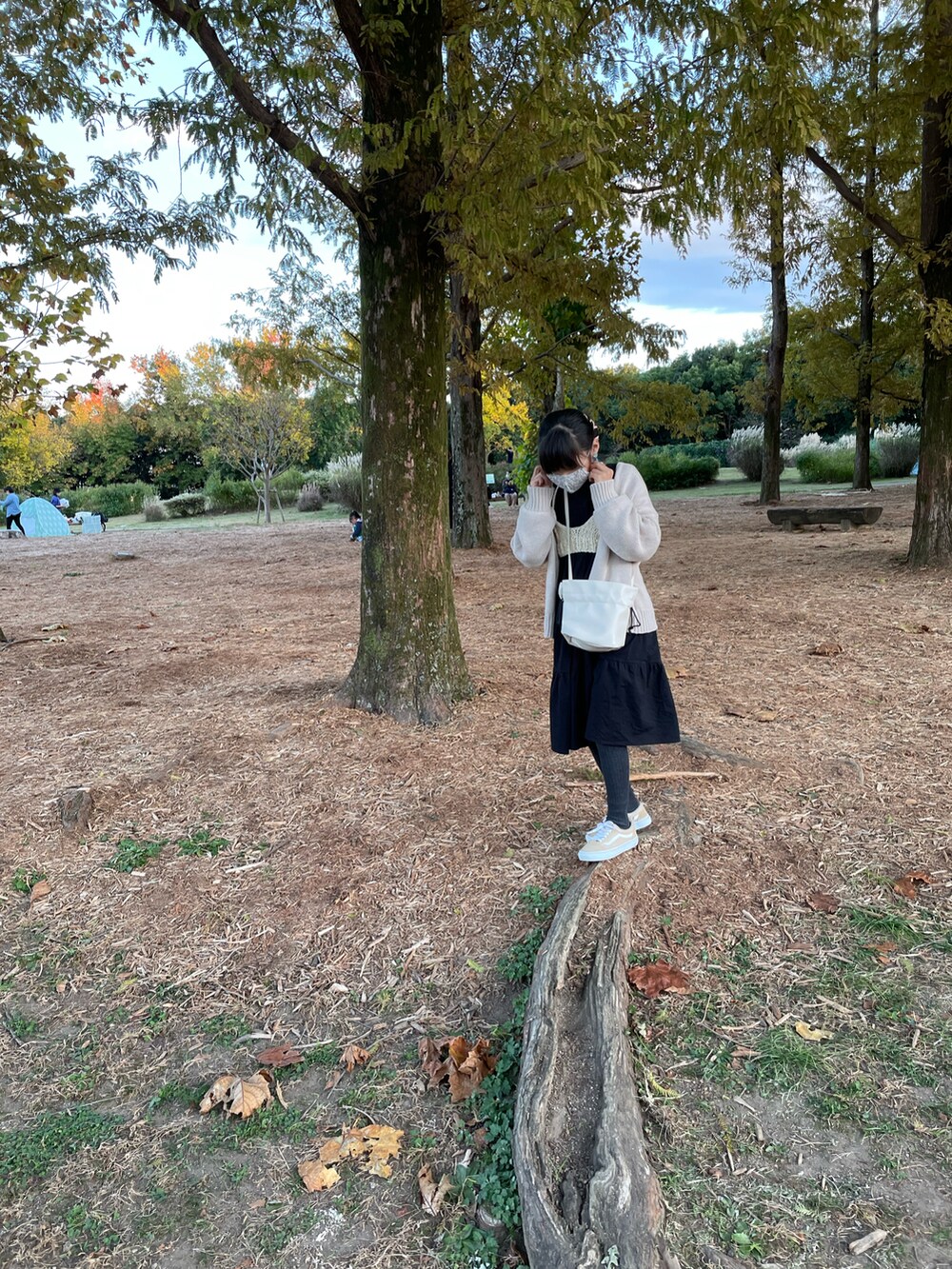 ブラック系のワンピース、ホワイト系のトップス、ベージュ系のスニーカーを着用したキッズの秋コーディネートの3枚目の写真