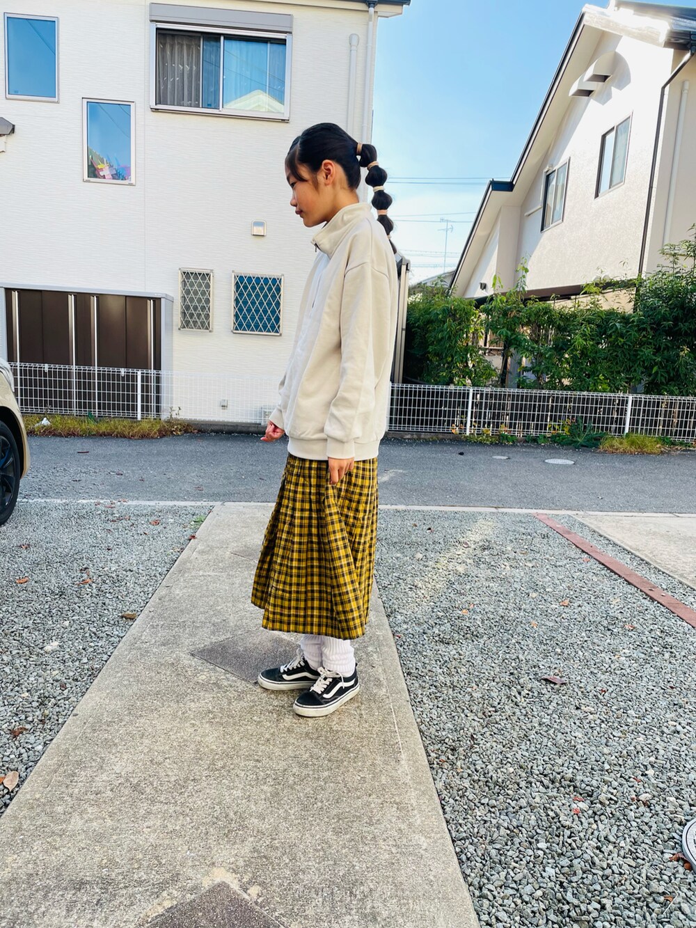 グレー系のスウェット、イエロー系のスカート、ブラック系のスニーカーを着用したキッズの秋コーディネートの3枚目の写真