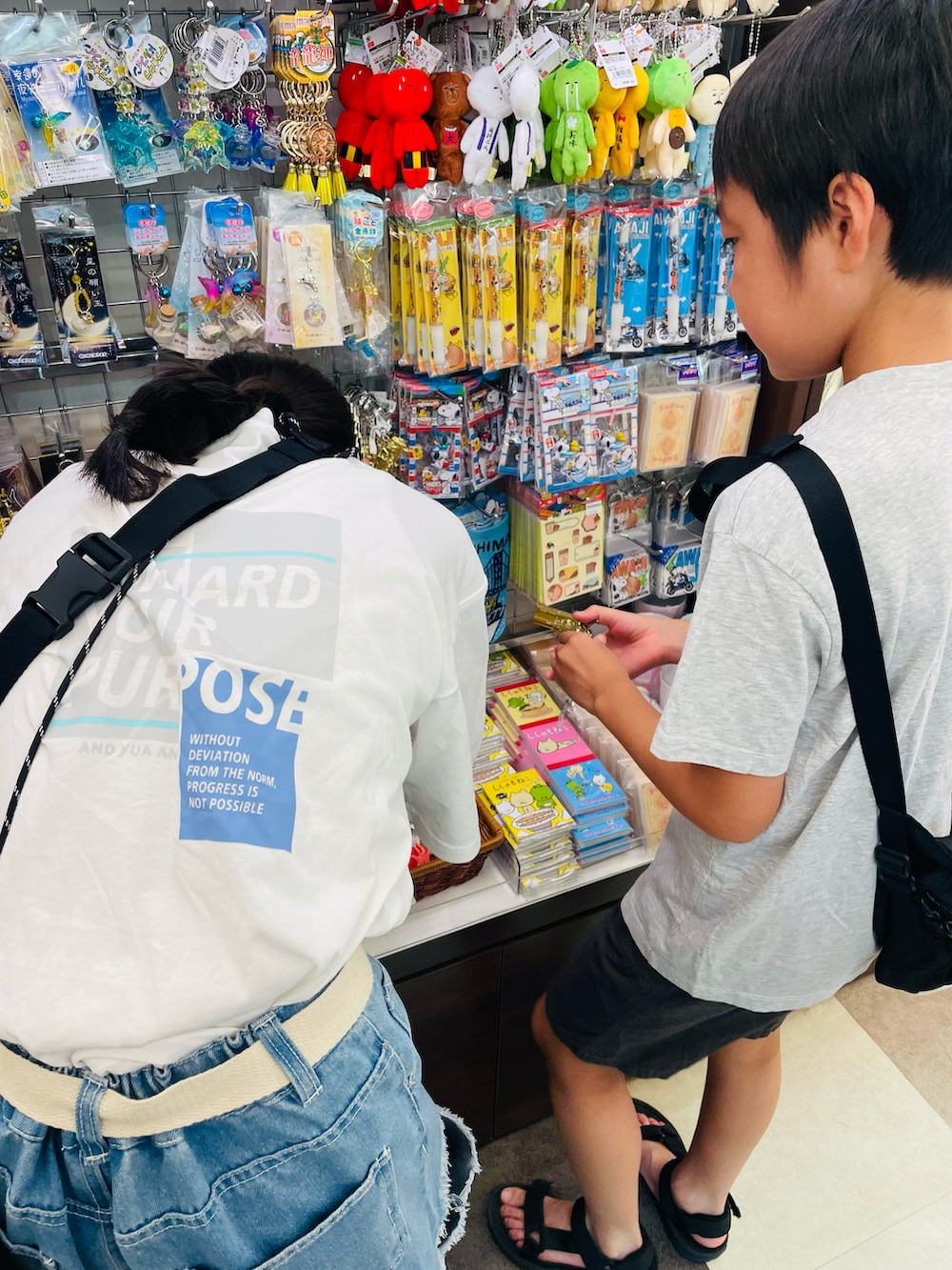 ホワイト系のTシャツ/カットソー、ブラック系のサンダル、ベージュ系のボディバッグ/ウエストポーチを着用したキッズの秋コーディネートの3枚目の写真