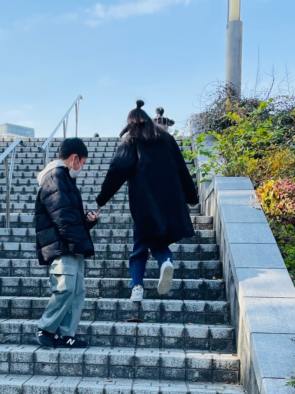 グレー系のスウェット、ブルー系のデニムパンツ、ホワイト系のスニーカーを着用したキッズの冬コーディネートの2枚目の写真