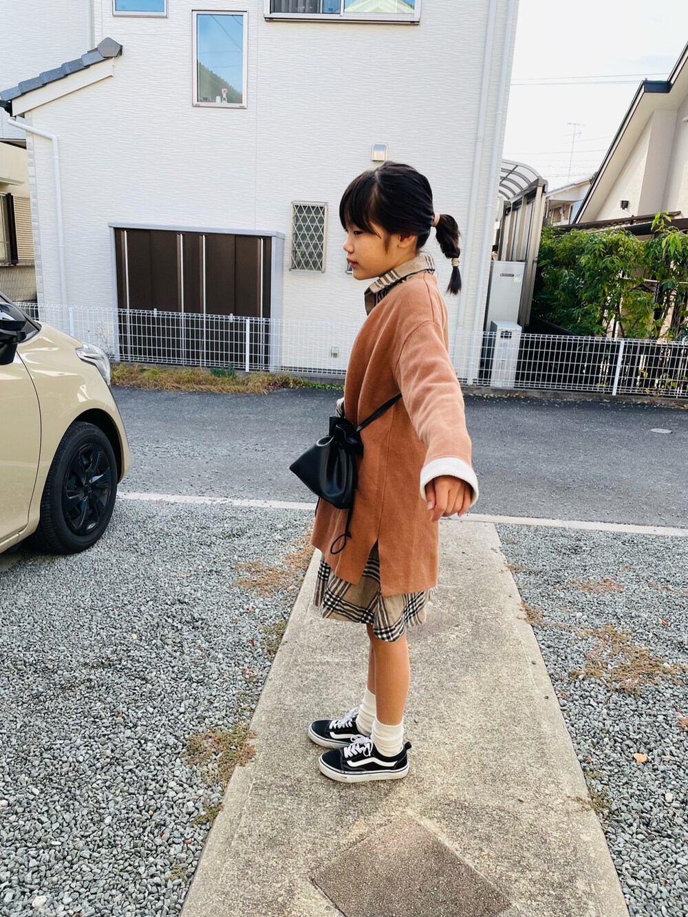 ブラック系のハンドバッグ、ブラック系のスニーカー、ブラウン系のシャツ/ブラウスを着用したキッズの秋コーディネートの2枚目の写真