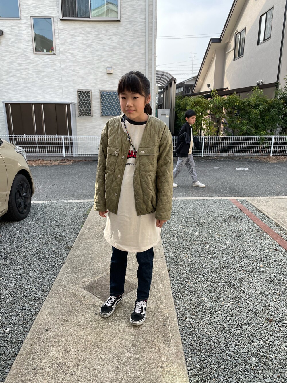 グリーン系のブルゾン、ブラック系のワンピース、ブルー系のデニムパンツを着用したキッズの春コーディネートの2枚目の写真