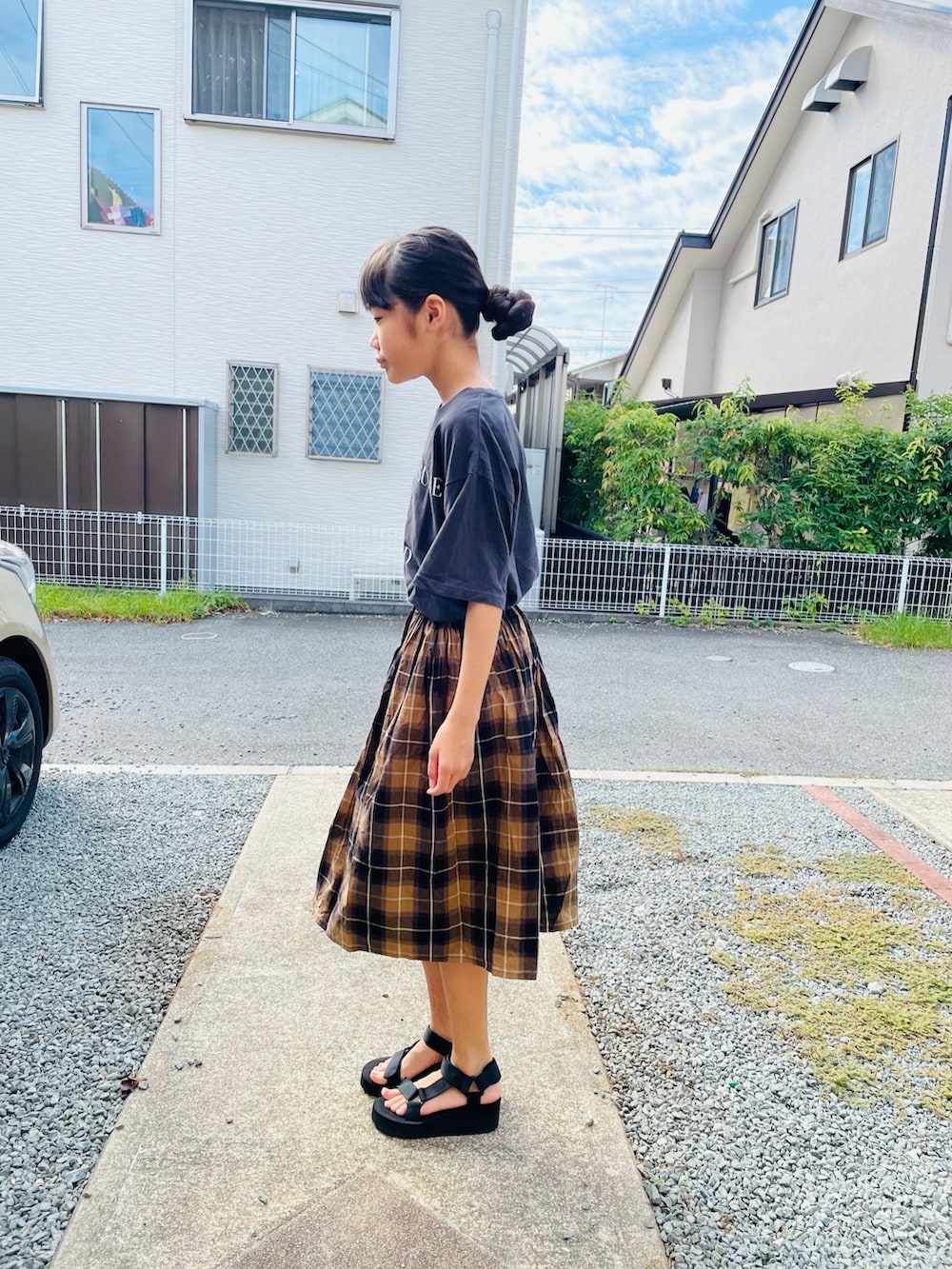 グレー系のTシャツ/カットソー、ブラウン系のスカート、ブラック系のサンダルを着用したキッズの秋コーディネートの2枚目の写真