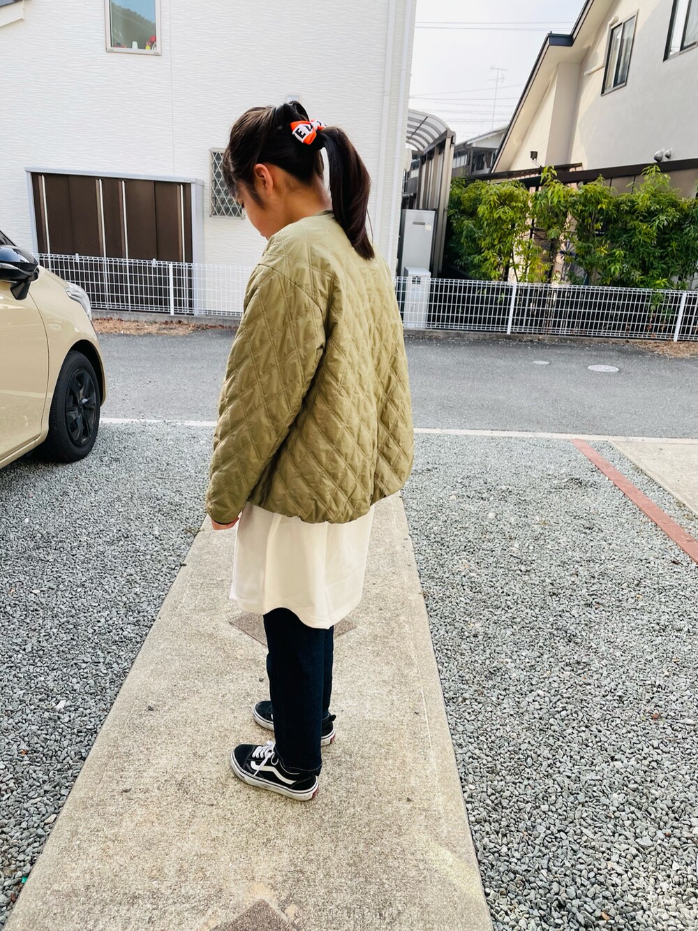 グリーン系のブルゾン、ブラック系のワンピース、ブルー系のデニムパンツを着用したキッズの春コーディネートの3枚目の写真