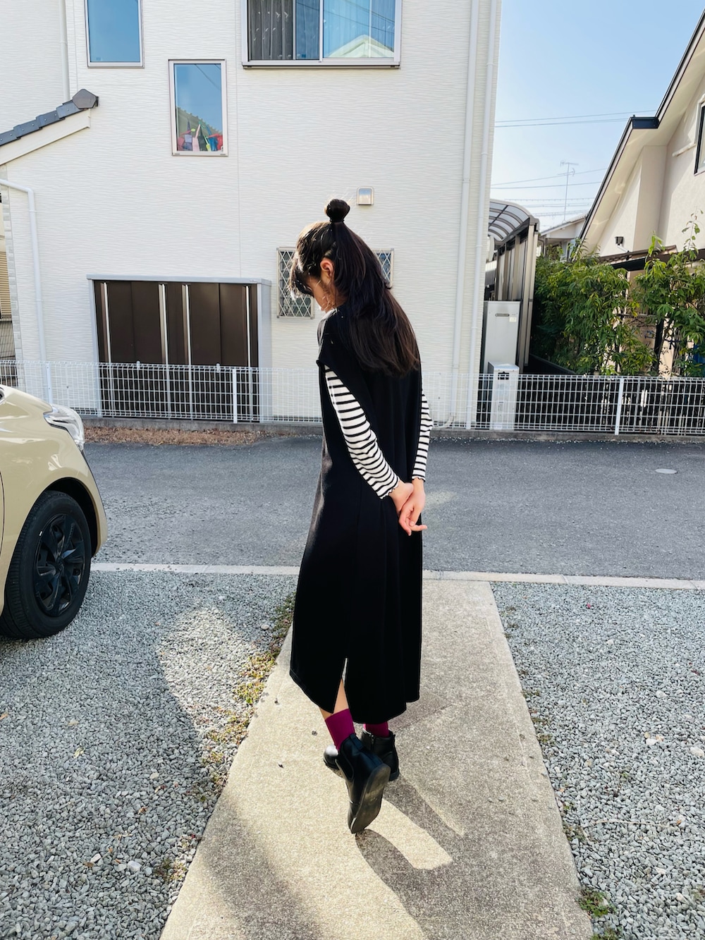 ブラック系のジャンパースカート、ブラック系のブーツを着用したキッズの春コーディネートの3枚目の写真