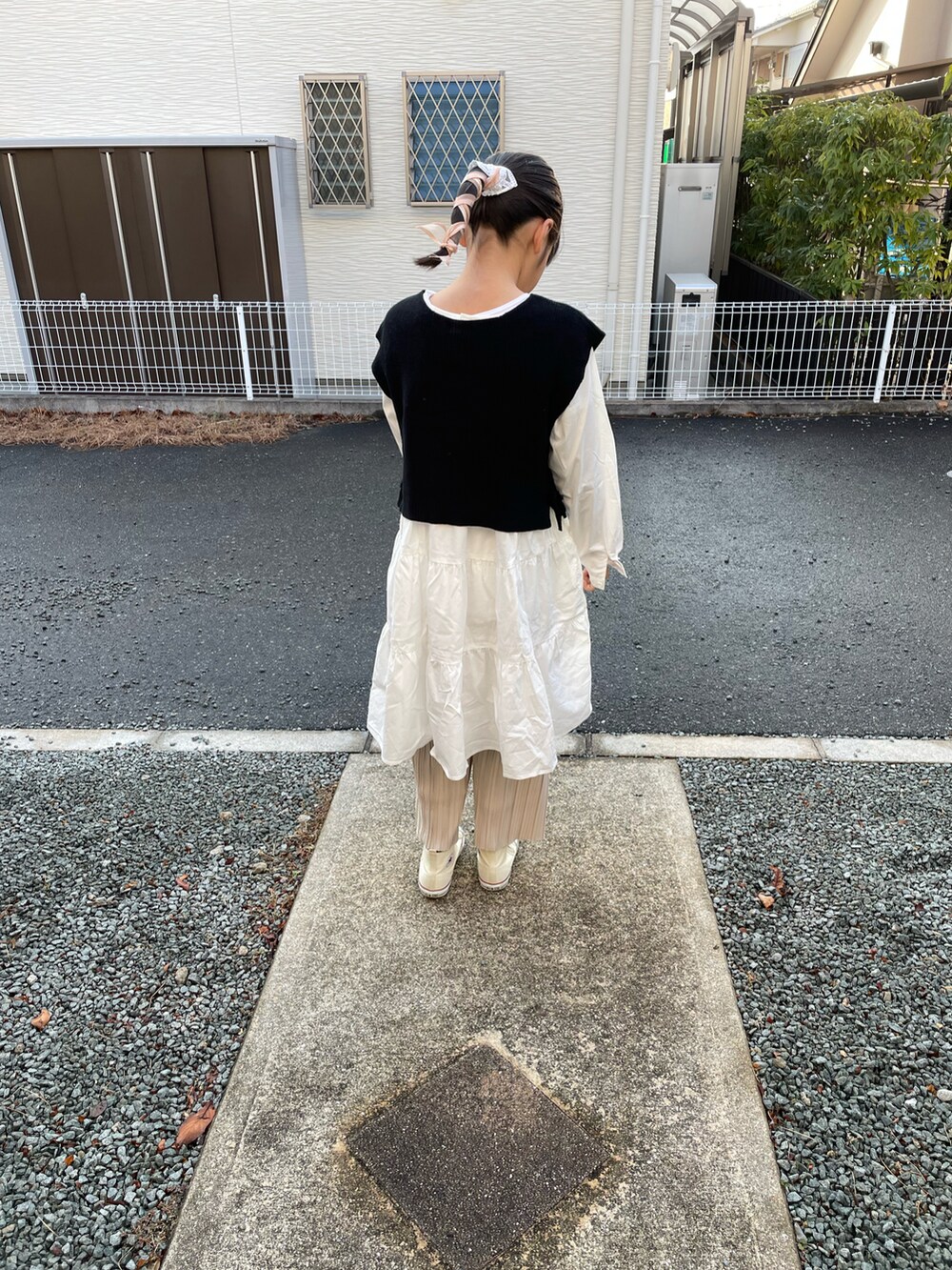 ホワイト系のワンピース、ブラック系のベスト、ベージュ系のその他パンツを着用したキッズの冬コーディネートの3枚目の写真