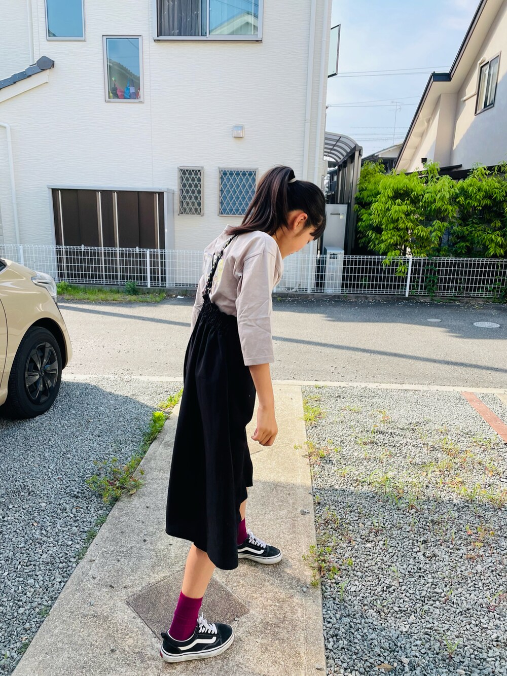 ブラック系のワンピース、ベージュ系のTシャツ/カットソー、ブラック系のスニーカーを着用したキッズの春コーディネートの2枚目の写真