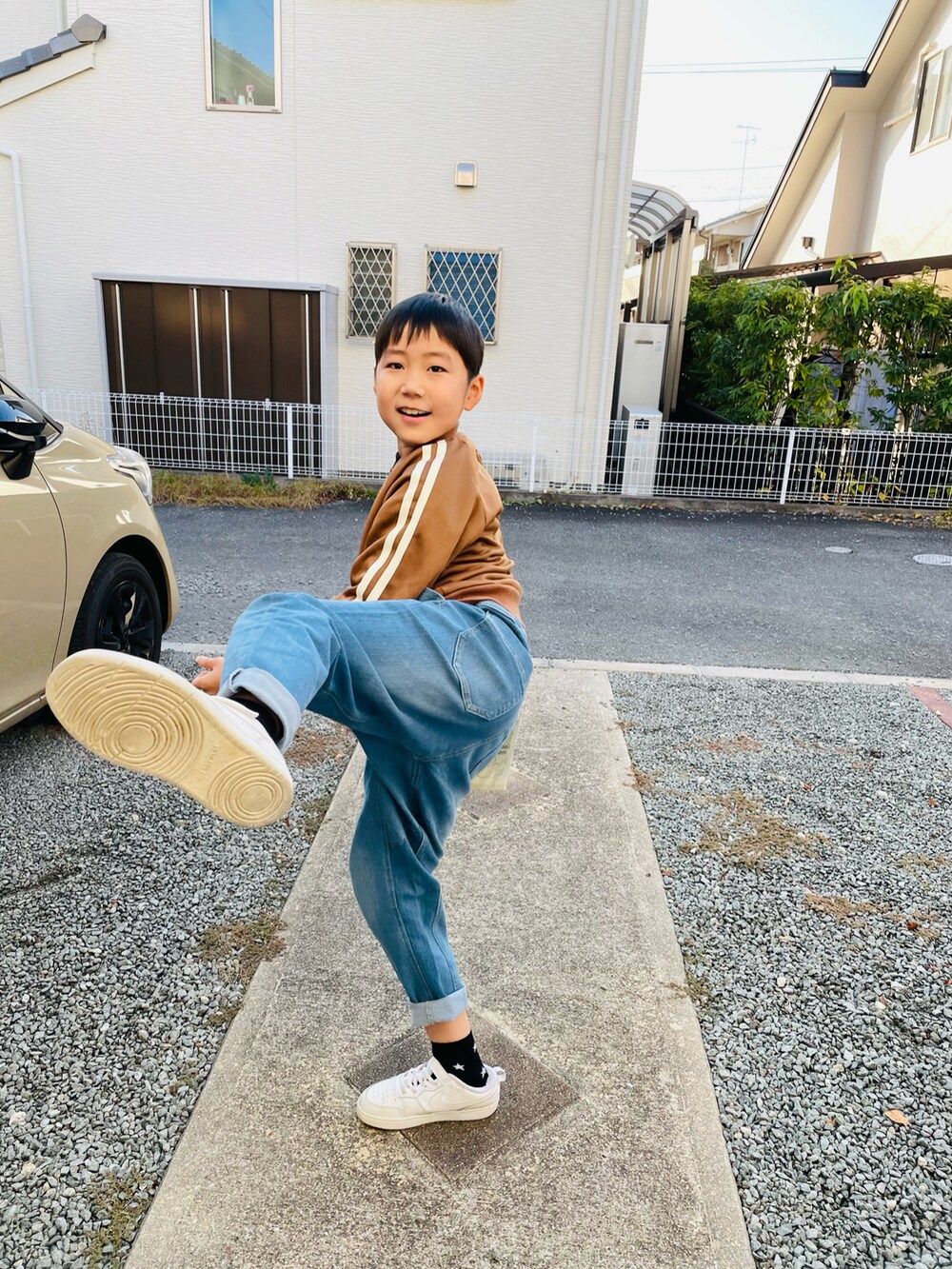 ブラウン系のノーカラージャケット、ブルー系のデニムパンツ、ホワイト系のスニーカーを着用したキッズの秋コーディネートの3枚目の写真