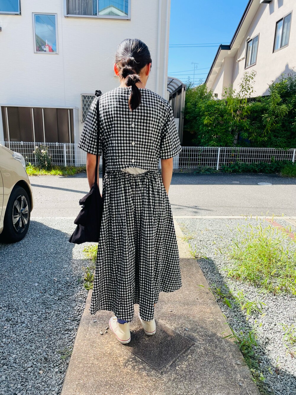 ブラック系のバッグ、ブラック系のワンピース、ホワイト系のスニーカーを着用したキッズの夏コーディネートの3枚目の写真