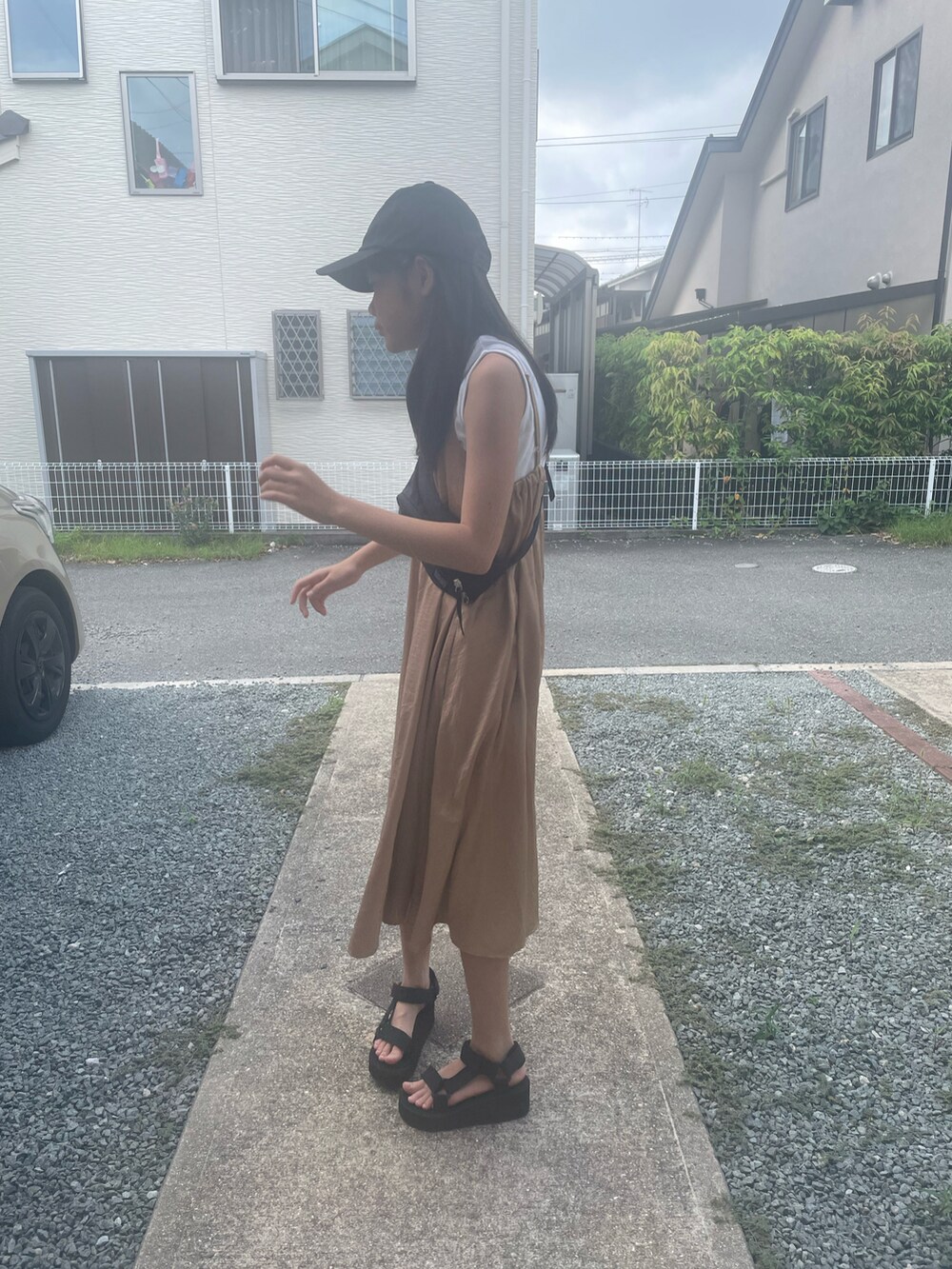 ベージュ系のジャンパースカート、ブラック系のサンダル、ブラック系のボディバッグ/ウエストポーチを着用したキッズの夏コーディネートの2枚目の写真