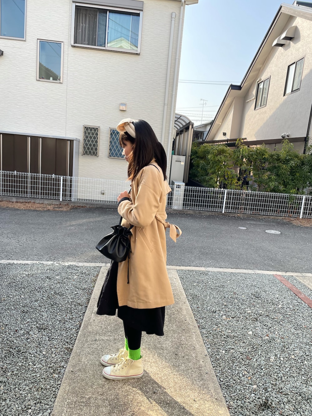 ベージュ系のトレンチコート、ブラック系のハンドバッグ、ブラック系のワンピースを着用したキッズの春コーディネートの2枚目の写真