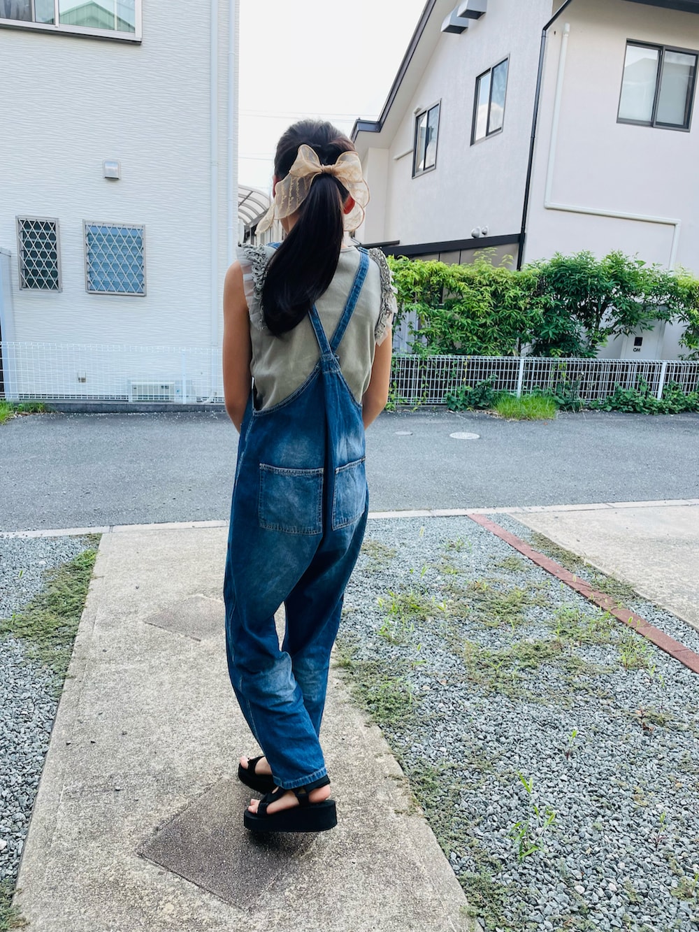 ブルー系のサロペット/オーバーオール、ブラック系のサンダル、グリーン系のタンクトップを着用したキッズの夏コーディネートの3枚目の写真