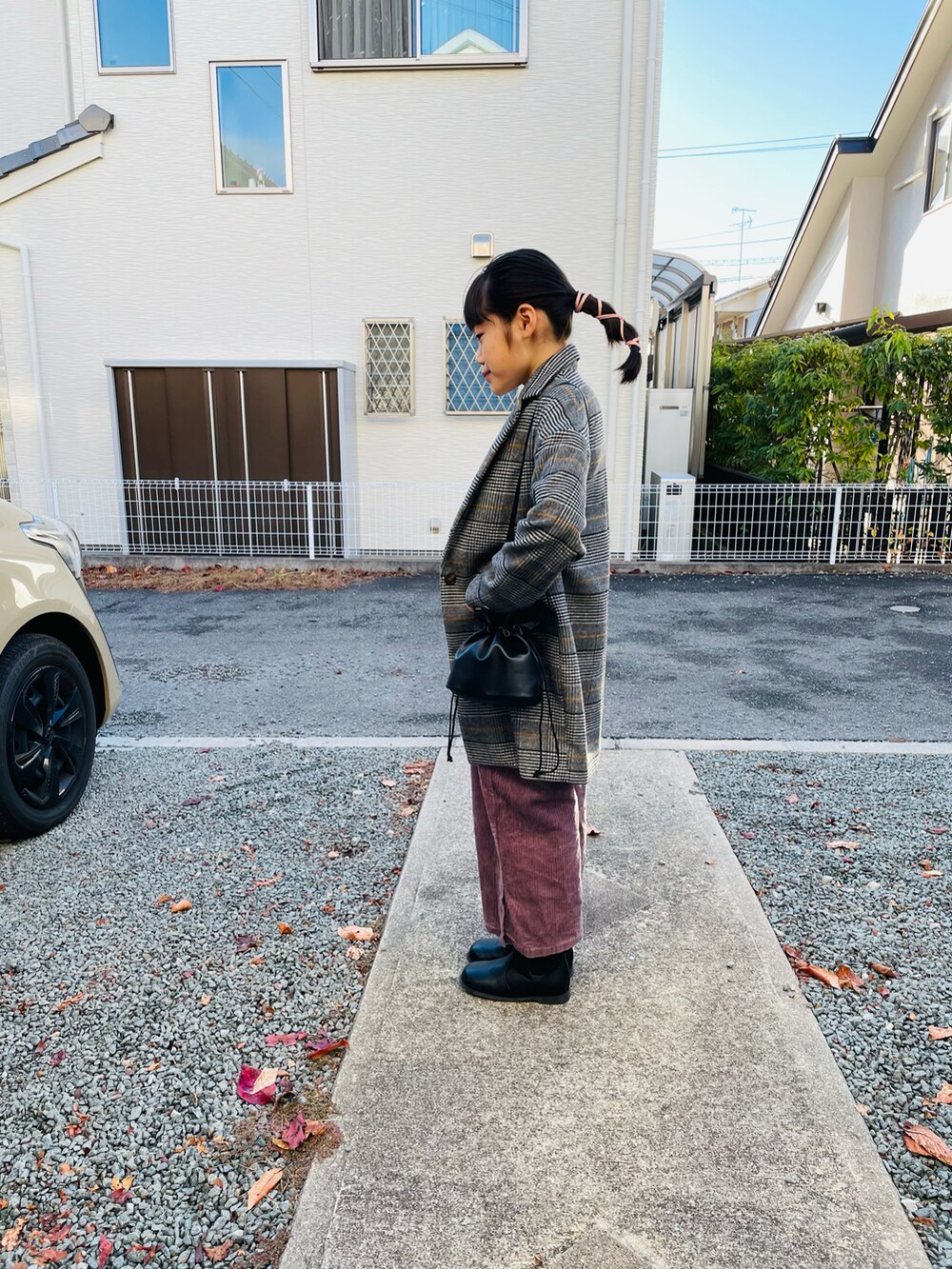 ホワイト系のTシャツ/カットソー、ブラック系のハンドバッグ、グレー系のチェスターコートを着用したキッズの秋コーディネートの2枚目の写真