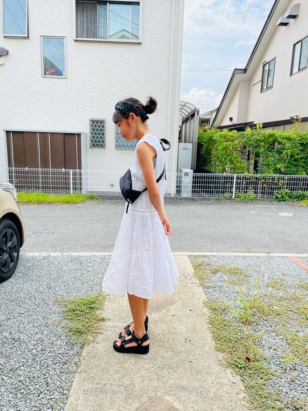 ホワイト系のワンピース、ブラック系のサンダル、ブラック系のボディバッグ/ウエストポーチを着用したキッズの夏コーディネートの2枚目の写真